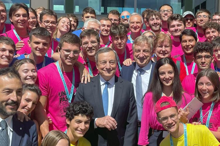 Mario Draghi con i giovani volontari del Meeting di Rimini e Bernhard Scholz, presidente della Fondazione 'Meeting Per L'Amicizia' (Fotogramma)