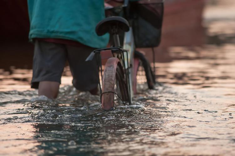 Uomo con bici in alluvione - Canva