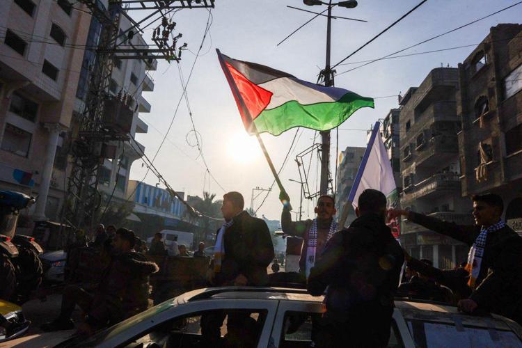 Un uomo sventola una bandiera palestinese mentre la gente festeggia l'accordo per il cessate il fuoco - (Afp)