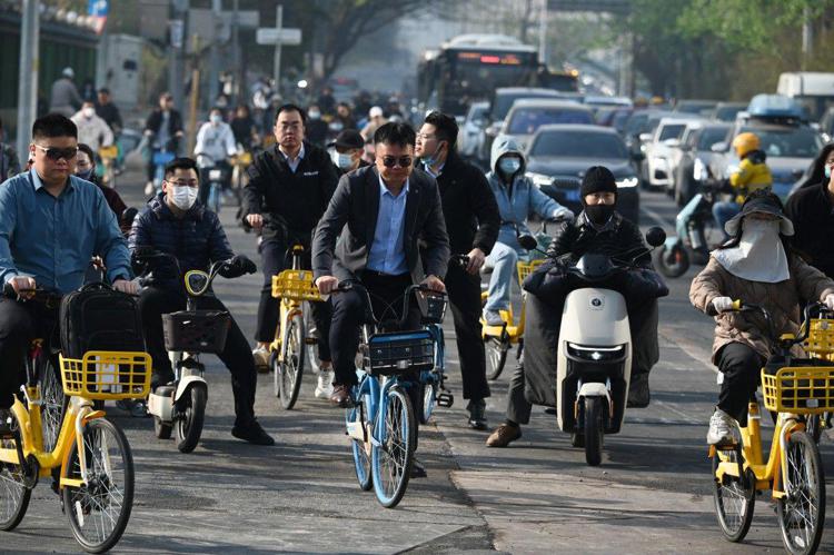 Persone attraversano una strada mentre si recano al lavoro nel quartiere centrale degli affari di Pechino  - (Afp)