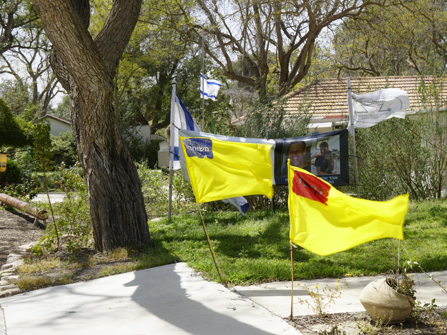 Viale nel quartiere degli abitanti più anziani di Nir Oz, Israele. Le bandiere gialle simboleggiano gli inquilini rapiti il sette ottobre. L'adesivo rosso denota la morte in cattività, quello blu l'avvenuta liberazione