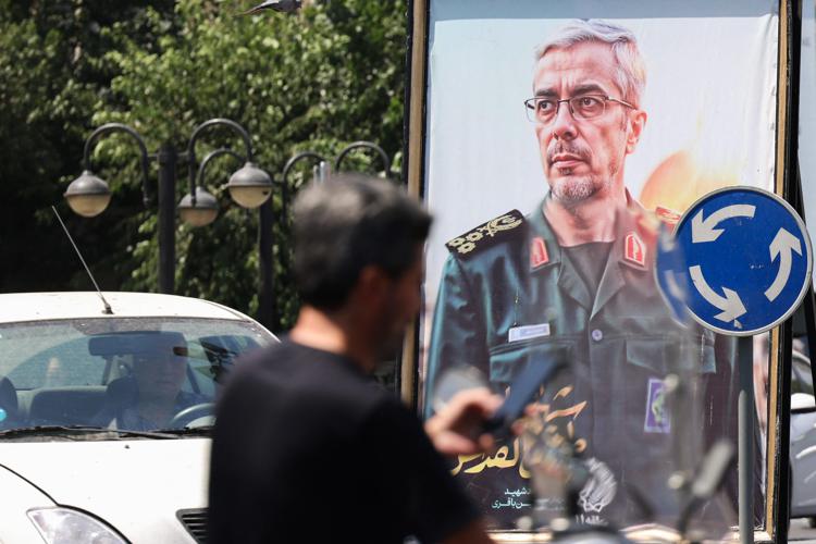 Una persona al telefono a Teheran, sullo sfondo l'immagine del generale Bagheri