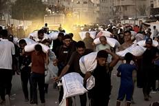Uomini camminano con sacchi di farina presi da un camion razziato che trasportava derrate alimentari, a Khan Yunis nel sud della striscia di Gaza - (Afp)