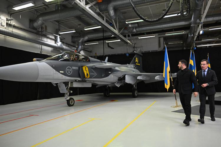 Il presidente ucraino Volodymyr Zelensky e il primo ministro svedese Ulf Kristersson davanti a un Gripen (Afp)
